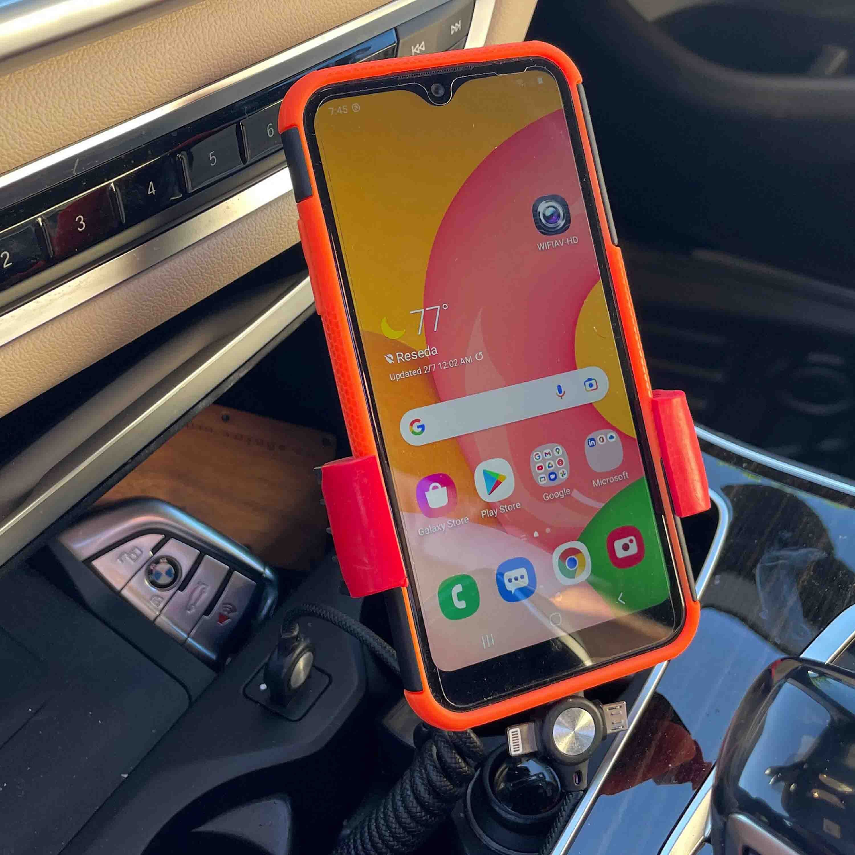 Smartphone secured on a cup holder phone mount inside a car, positioned for easy navigation viewing during driving.